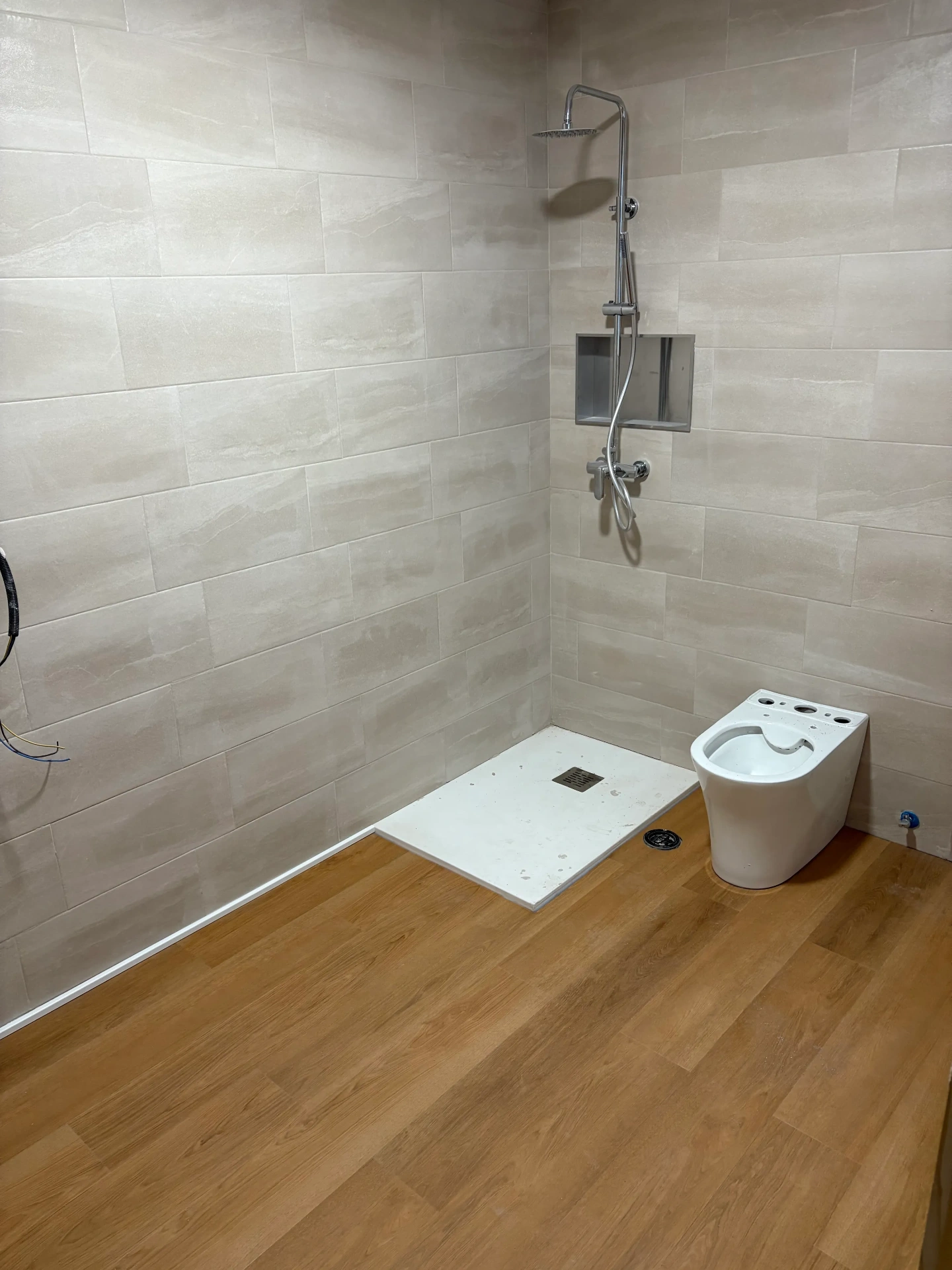 Baño con plato de ducha de obra y suelo de tarima de madera